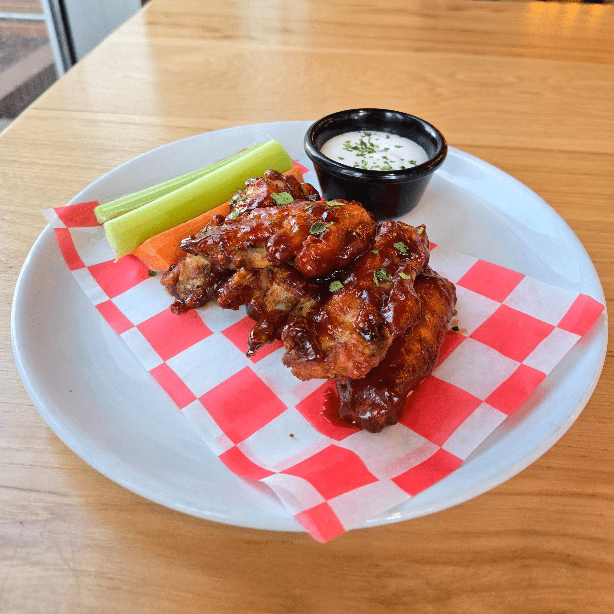 Image depicts 10 barbeque wings, served with celery, carrots and your choice of ranch or bleu cheese dipping sauce.