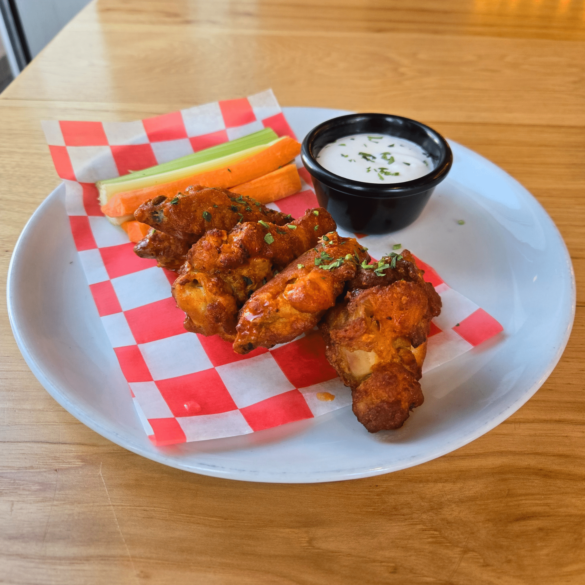 Image depicts 10 buffalo wings, served with celery, carrots and your choice of ranch or bleu cheese dipping sauce.